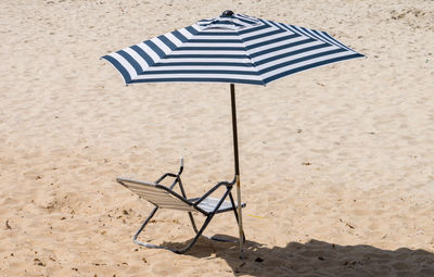 High angle view of deck chair and parasol on sandy beach during sunny day