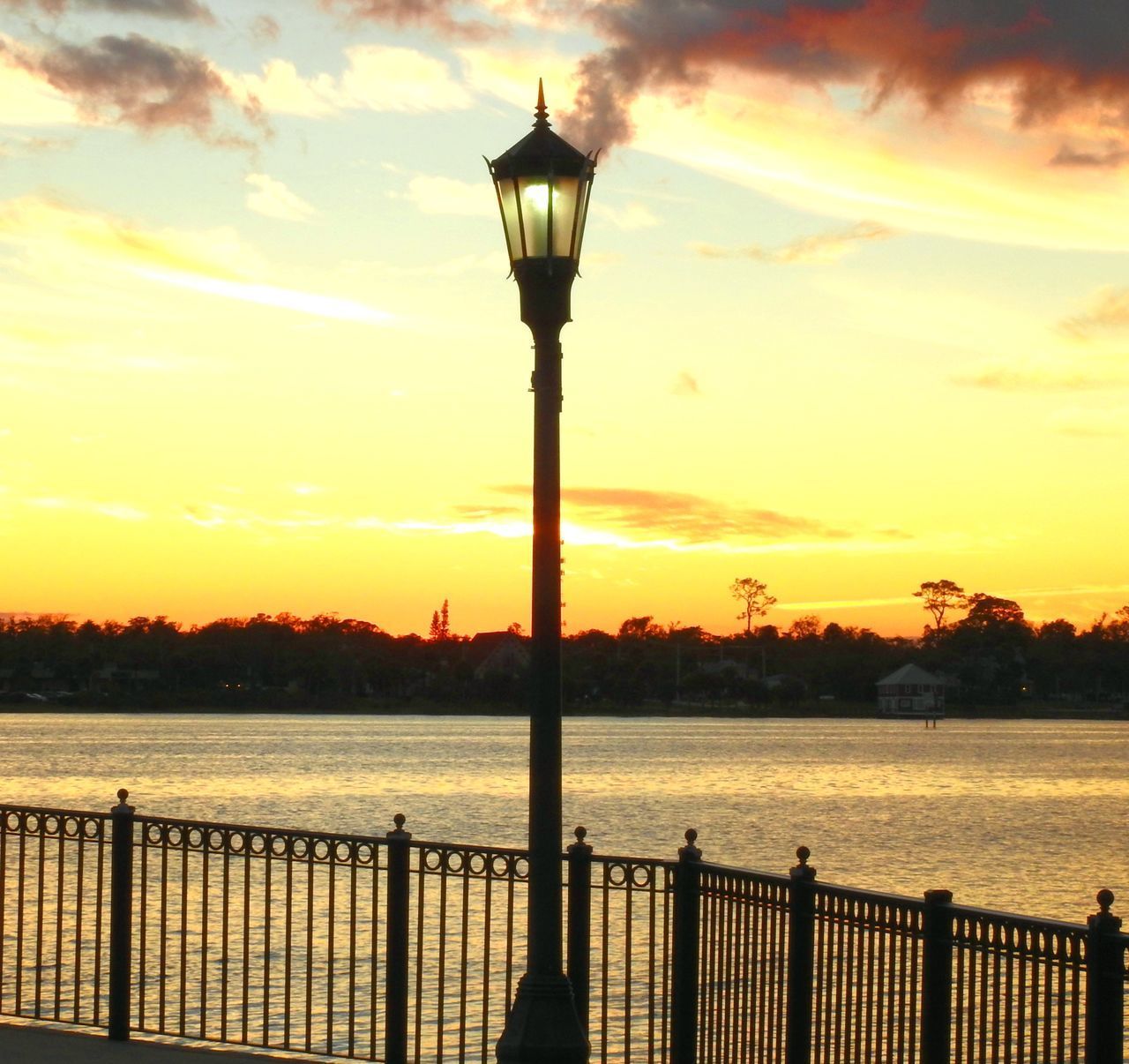 STREET LIGHT BY SEA AGAINST SKY DURING SUNSET