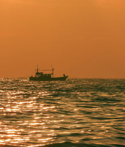 Boat sailing in sea against sky during sunset