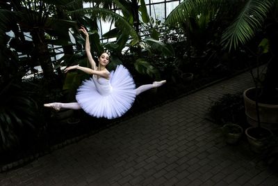 Ballet dancer dancing against trees at park