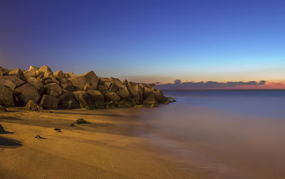 View of calm beach against clear blue sky