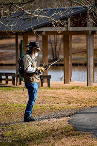 Side view of mature man holding equipment standing at park