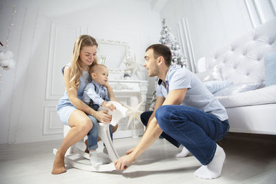 Cheerful parents playing with son at home