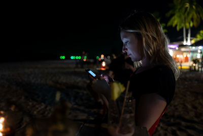 Woman using mobile phone in city at night