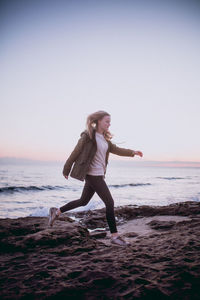 Full length of young woman on beach against clear sky