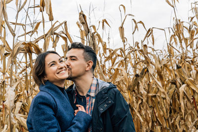 Happy couple in love in autumn in a cornfield. a man kisses a woman on the cheek