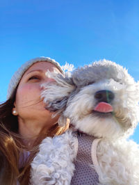 Portrait of woman with dog against clear blue sky