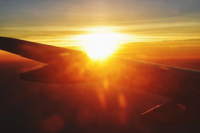 Close-up of airplane wing against sky during sunset