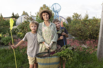 Senior woman holding basket standing with grandchildren in garden