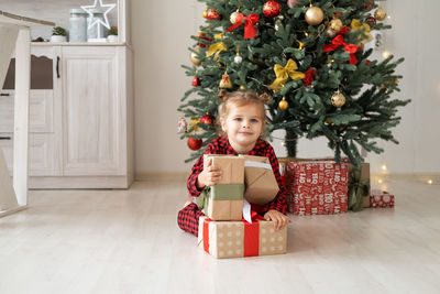 Portrait of smiling woman with christmas presents at home