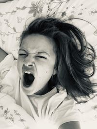 High angle view of woman yawning while lying on bed