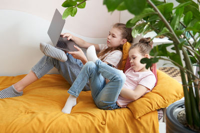 Sisters using laptop while lying in bed