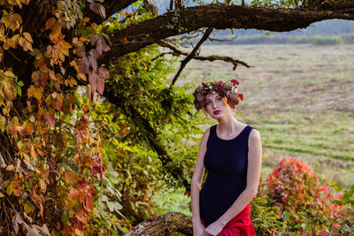 Woman wearing flowers while standing near tree