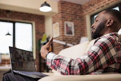 Side view of man using mobile phone while sitting at cafe