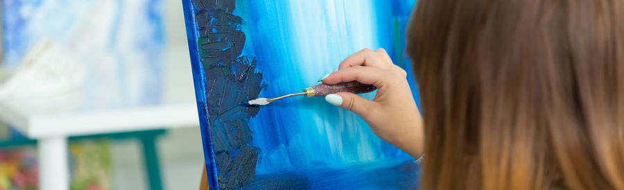 Close-up of woman hand against blue wall