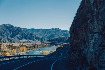 Road by mountains against clear sky