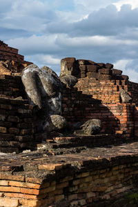 Low angle view of old ruin building against cloudy sky