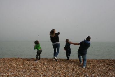 Rear view of people throwing stones at sea