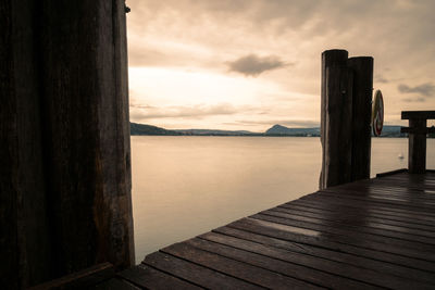 Wooden pier over lake against sky during sunset