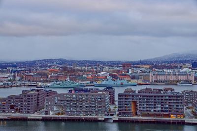 High angle view of buildings by river against sky