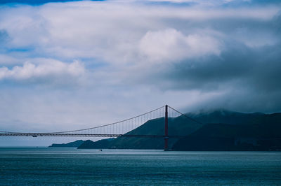 Suspension bridge over sea against sky