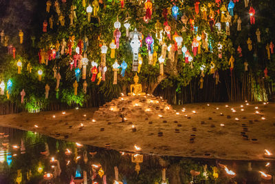 Panoramic view of illuminated trees by lake at night