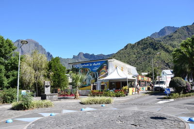 Road by buildings against clear blue sky