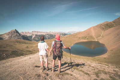 Rear view of couple standing on mountain against sky