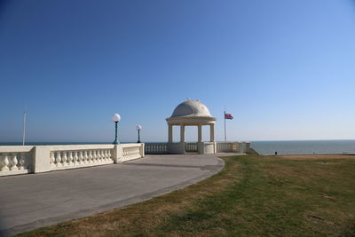 Gazebo by sea against clear blue sky