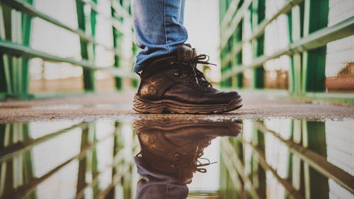 Low section of man standing on wet railing