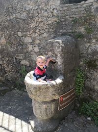 Portrait of smiling boy sitting in drinking fountain 