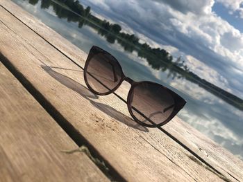 Sunglasses on wooden floor against sky