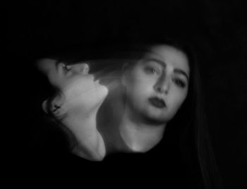 Close-up of young woman against black background