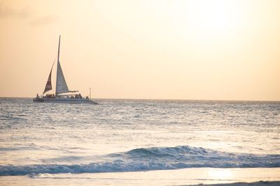 Sailboat sailing on sea against sky during sunset