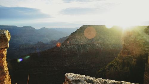 Scenic view of rocky mountains against sky on sunny day seen through glass