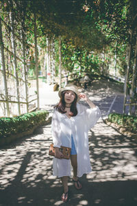 Portrait of smiling young woman standing against trees