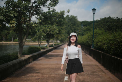 Portrait of young woman standing against trees