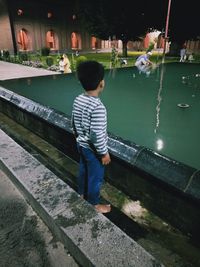 Rear view of boy standing in canal