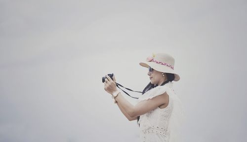 Side view of woman holding umbrella against white background