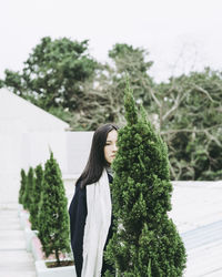 Young woman standing by tree