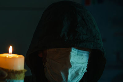 Rear view of man standing against illuminated candles