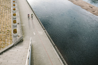 High angle view of people riding bicycles on road by river