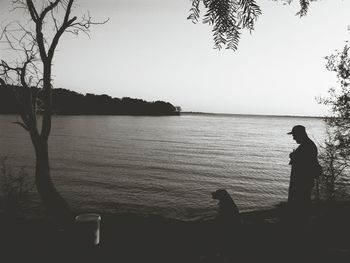 Silhouette man looking at lake against sky