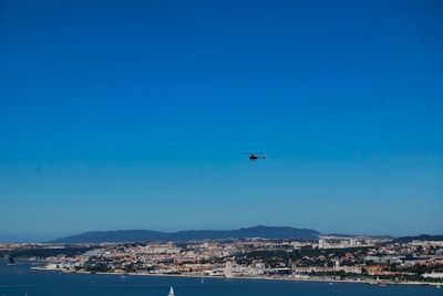 Airplane flying over city against blue sky