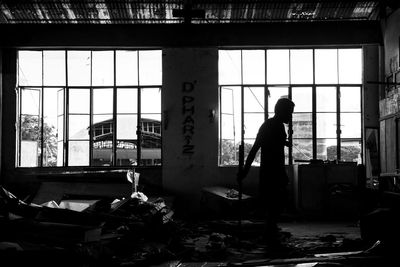 Silhouette man standing by window