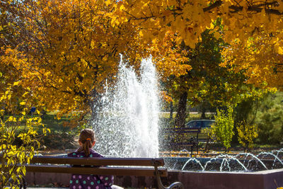 Rear view of woman looking at waterfall during autumn
