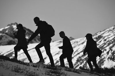 Silhouette people uphill hiking against mountain