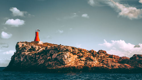 Lighthouse by sea against sky