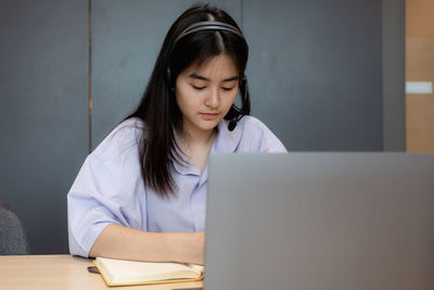 Mid adult woman using mobile phone while sitting on table