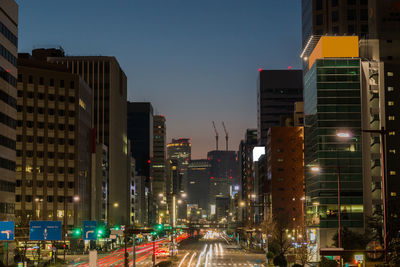 City street amidst buildings against sky at dusk